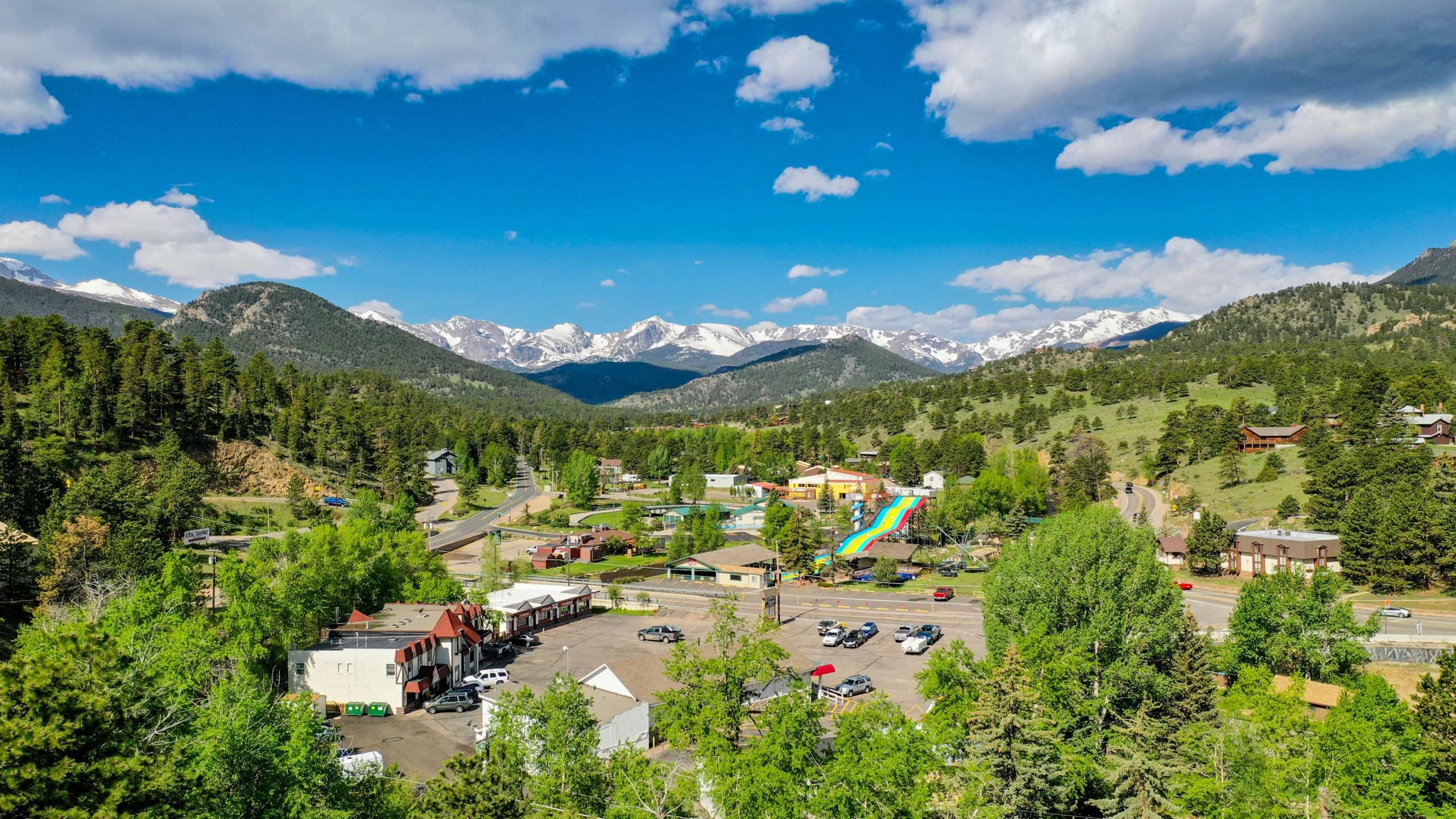 This is an image from 100' above This Mountain Life Basecamp looking south to southwest with Piccadilly Square, Rock Cut Brewery, Fun City, Estes Park Brewery in the foreground and the Continental Divide 9 miles afar under snow.